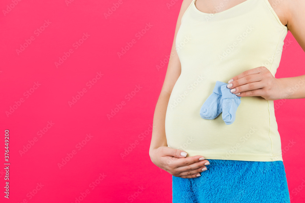 custom made wallpaper toronto digitalClose up portrait of pregnant woman in colorful home clothing holding blue socks for a baby boy at pink background. Future child expectation concept. Copy space