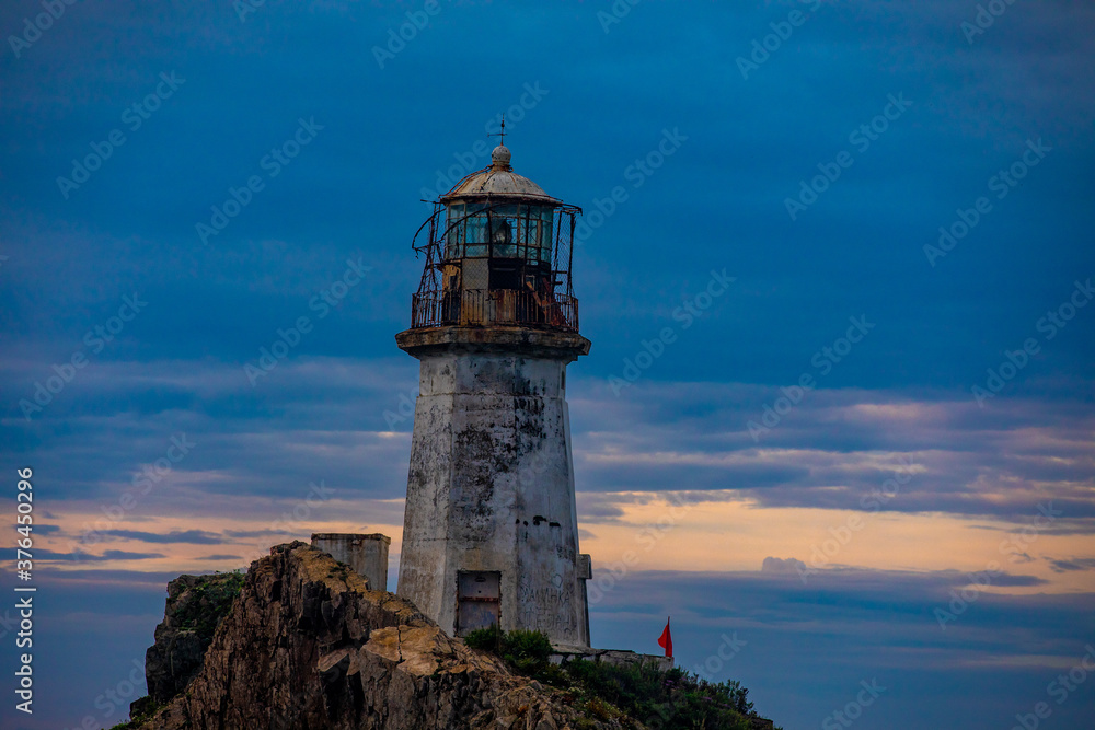 Rudny lighthouse at Cape Briner in the village of Smychka (Rudnaya Pristan), Primorsky Territory. The beautiful Rudny lighthouse stands on a sheer cliff against the backdrop of a bright dawn