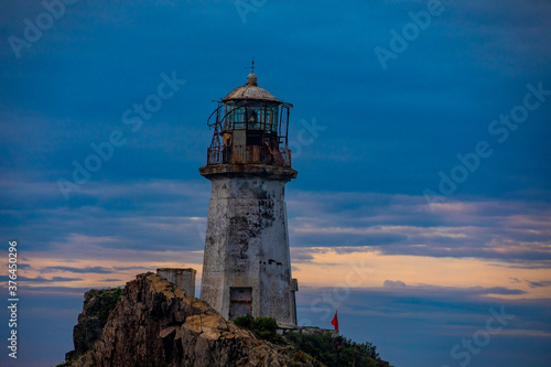 Rudny lighthouse at Cape Briner in the village of Smychka (Rudnaya Pristan), Primorsky Territory. The beautiful Rudny lighthouse stands on a sheer cliff against the backdrop of a bright dawn © alexhitrov
