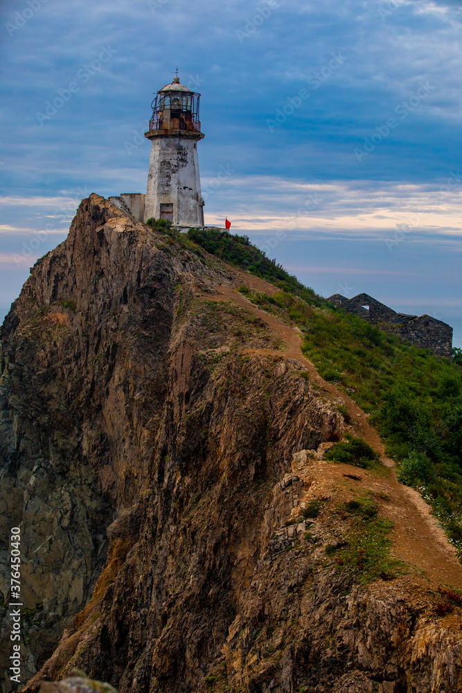 Rudny lighthouse at Cape Briner in the village of Smychka (Rudnaya Pristan), Primorsky Territory. The beautiful Rudny lighthouse stands on a sheer cliff against the backdrop of a bright dawn