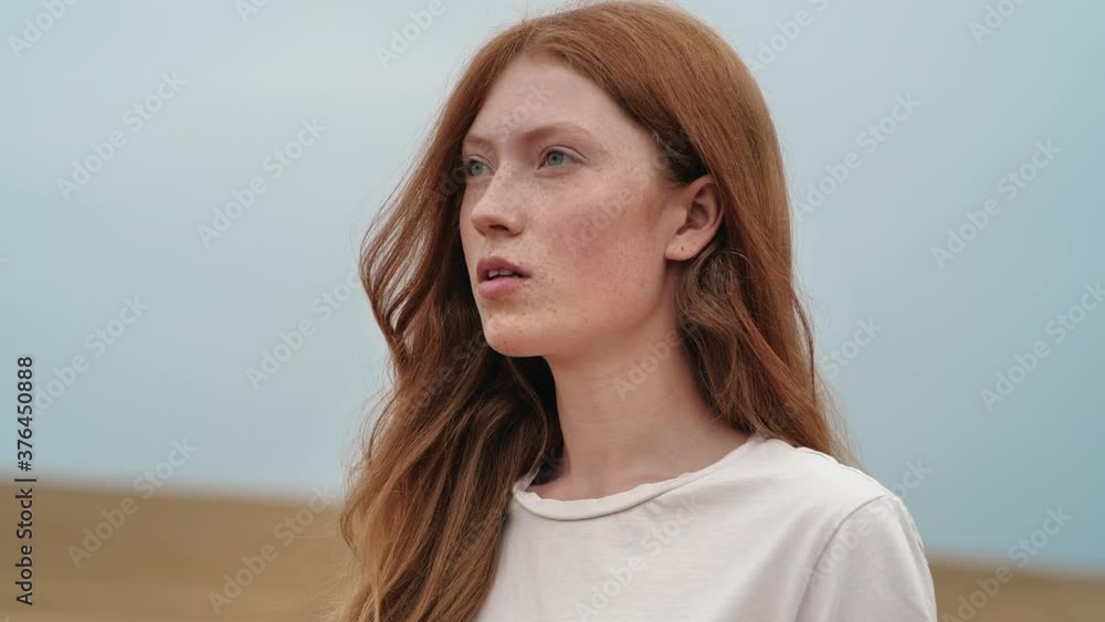 Beautiful Woman Ginger opening her Eyes while looking at Nature, having long nice Eyelashes. Attractive girl with nice Freckles on her Beautiful Face. Red-haired woman with walking on gold Field. Beautiful Woman Ginger opening her Eyes while looking at Nature, having long nice Eyelashes. Attractive girl with nice Freckles on her Beautiful Face. Red-haired woman with walking on gold Field.
