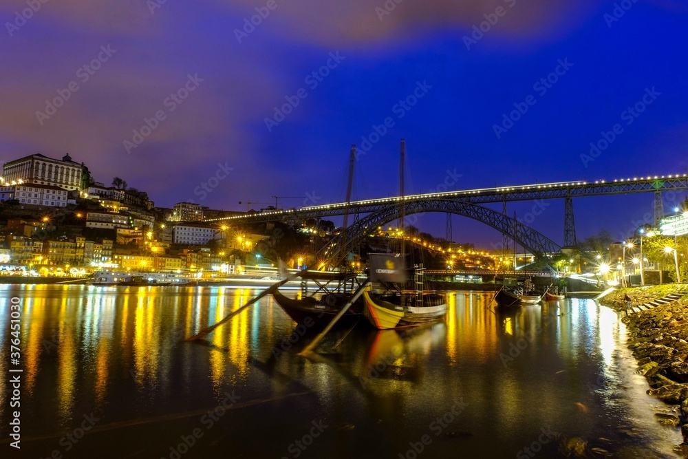 Beautiful Porto cityscape at night with boats and bridge over the river