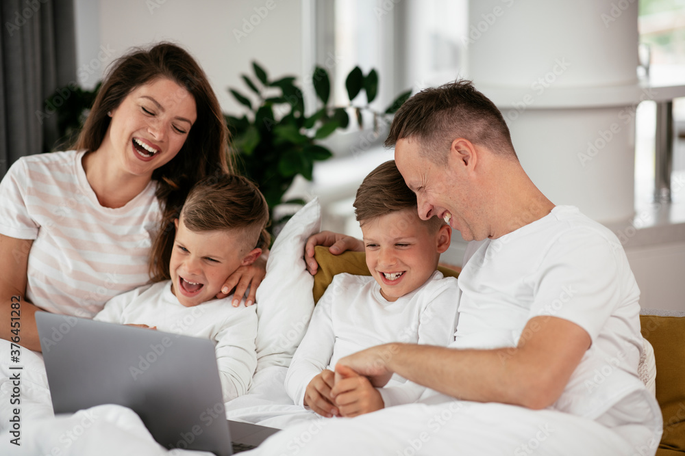 Beautiful parents with kids enjoying at home. Young family watching movie on lap top.. Beautiful parents with kids enjoying at home. Young family watching movie on lap top..