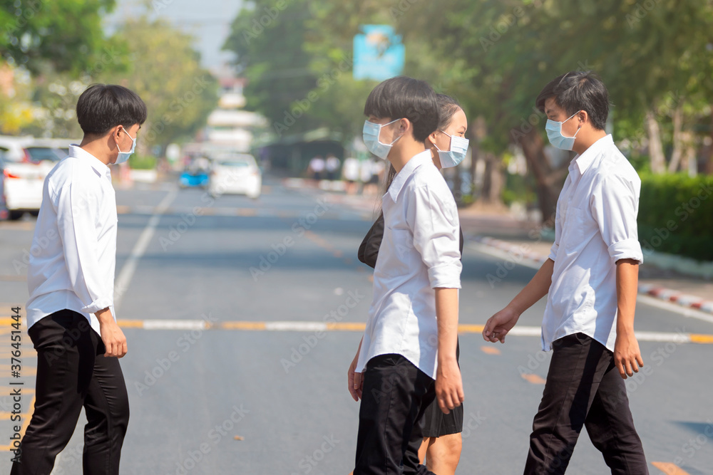 Group of Asian student in protective masks against covid19, flu, pollution, contagious diseases walking in the city street. Selective Focus Group of Asian student in protective masks against covid19, flu, pollution, contagious diseases walking in the city street. Selective Focus