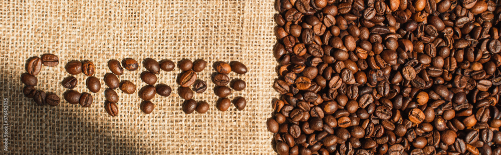 top view of coffee lettering made of beans in sunlight on sackcloth, panoramic shot top view of coffee lettering made of beans in sunlight on sackcloth, panoramic shot