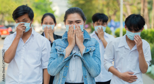 Group of Asian people in protective masks against covid19, flu, pollution, contagious diseases walking in the city street. Panorama