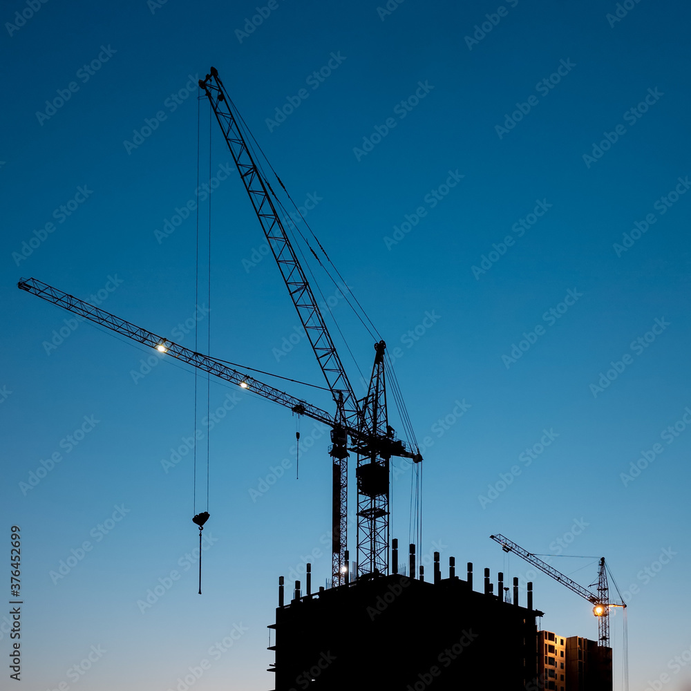 Construction crane at evening time on the blue sky with no clouds. Residential buildings construction at evening time minimalistic photo
