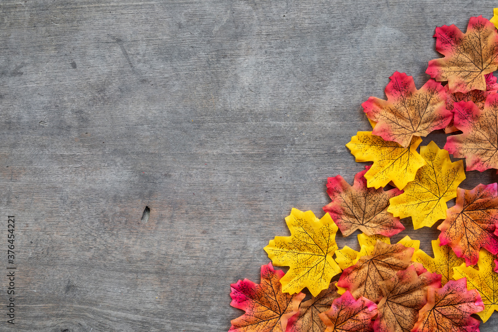 colorful autumn plastic leaves on old wooden floor background. top view. flat lay
