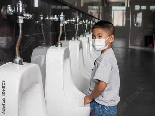 Canvas Print Boy wearing a protective face He is urinating in the public toilet