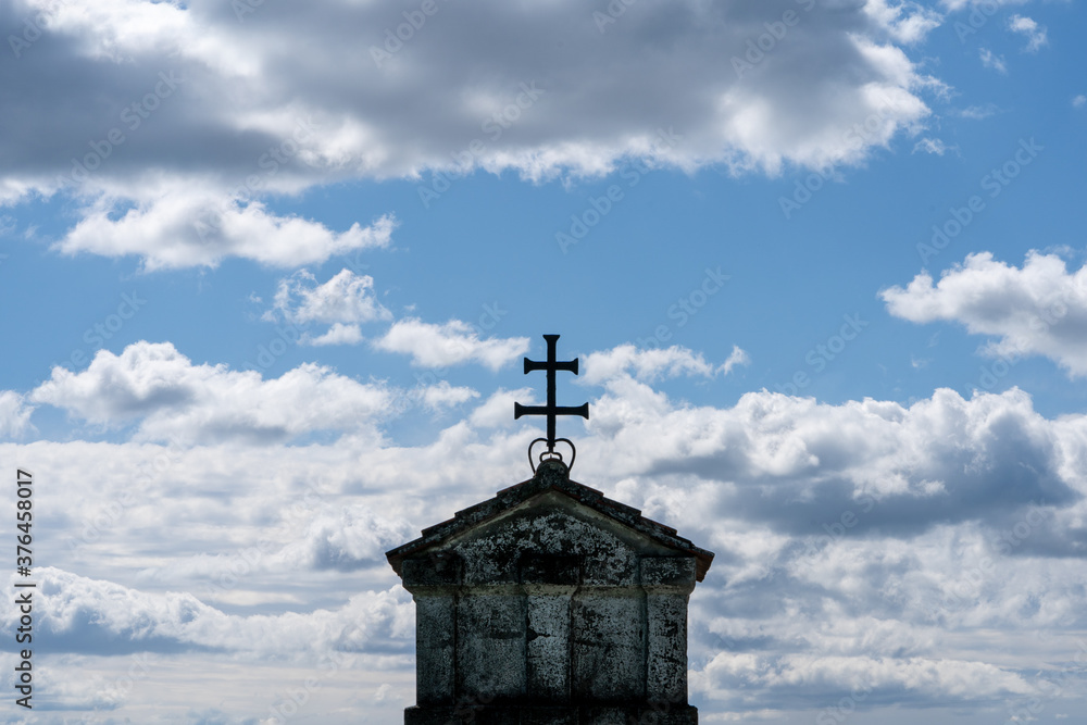 Close Up eines Daches mit Kreuz mit bewölktem Himmel im Hintergrund
