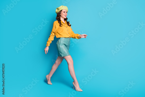 Full size profile side photo of attractive sweet lady go walk copyspace enjoy rest relax wear good look clothes shoes headwear isolated over blue color background