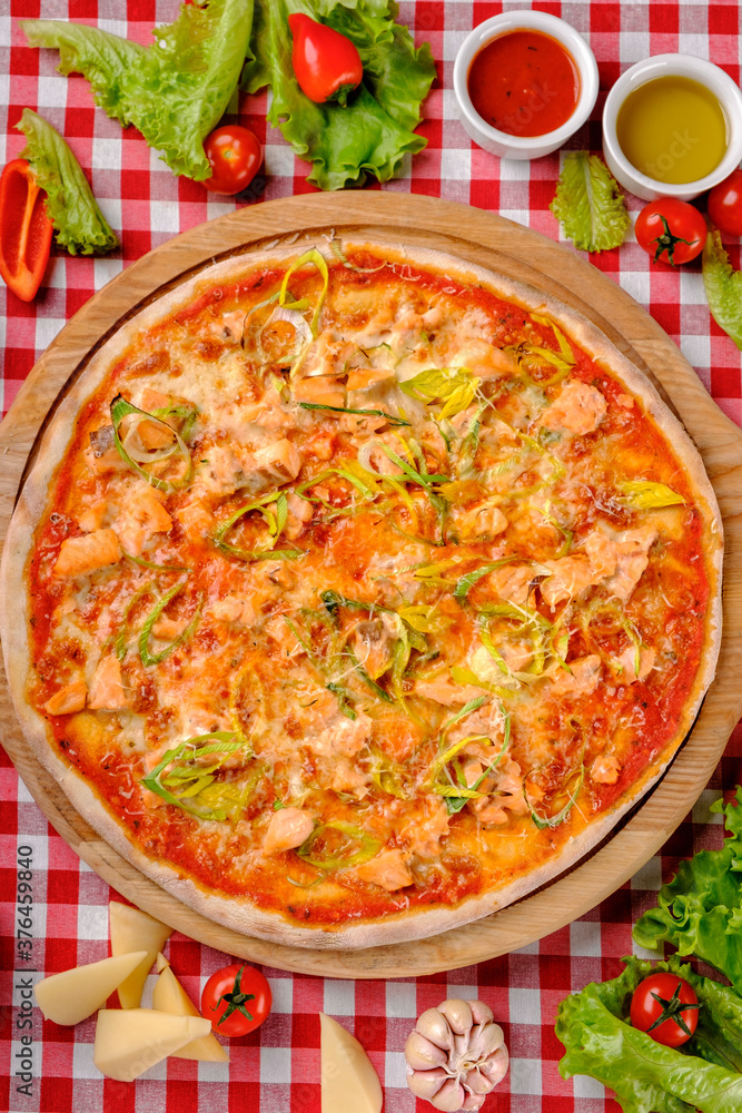 Rustic pizza with atlantic salmon, cheese, tomato, leek and tomatoes sauce in italian restaurant background, top view. Classic Italy food. Pizza from wooden oven. Close up Rustic pizza with atlantic salmon, cheese, tomato, leek and tomatoes sauce in italian restaurant background, top view. Classic Italy food. Pizza from wooden oven. Close up