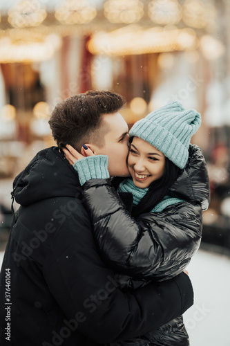 Obraz na płótnie Happy man kissing and embracing smiling woman in winter in city. Love, winter holidays and people concept. w salonie