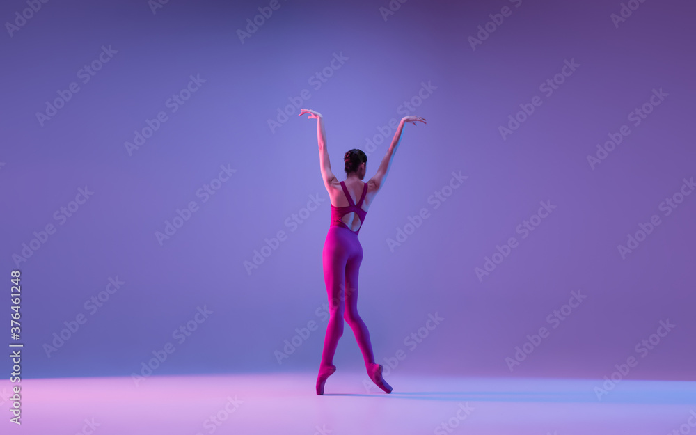 Freedom. Young and graceful ballet dancer isolated on purple studio background in neon light. Art, motion, action, flexibility, inspiration concept. Flexible caucasian ballet dancer, weightless jumps. Freedom. Young and graceful ballet dancer isolated on purple studio background in neon light. Art, motion, action, flexibility, inspiration concept. Flexible caucasian ballet dancer, weightless jumps.
