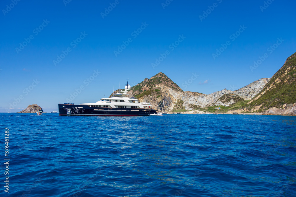 Palmarola island (Ponza, Latina), Italy: view of the rocky coast with a wonderful luxury yacht in the foreground.