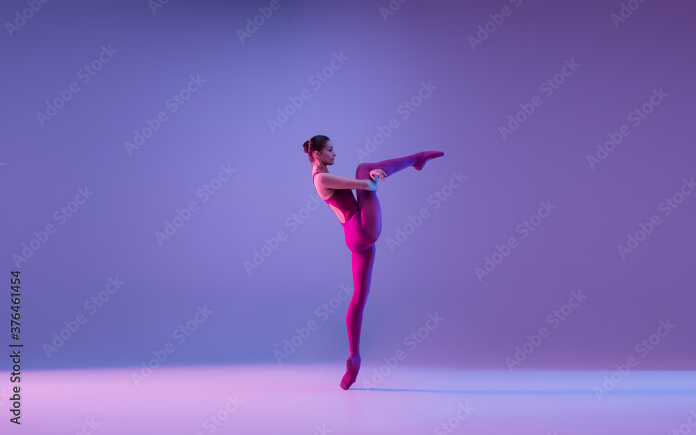 Tender. Young and graceful ballet dancer isolated on purple studio background in neon light. Art, motion, action, flexibility, inspiration concept. Flexible caucasian ballet dancer, weightless jumps. Tender. Young and graceful ballet dancer isolated on purple studio background in neon light. Art, motion, action, flexibility, inspiration concept. Flexible caucasian ballet dancer, weightless jumps.