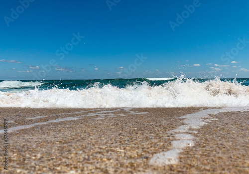 Sea wave crashing to the sandy shore creating line between the beach and the sky