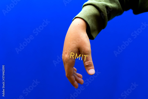 Boy human hand an adhesive transparent tape is glued to it.Blue studio background.RMIT Inscriptions on the tape.