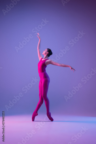 Fototapeta Naklejka Na Ścianę i Meble -  Dynamic. Young and graceful ballet dancer isolated on purple studio background in neon light. Art, motion, action, flexibility, inspiration concept. Flexible caucasian ballet dancer, weightless jumps.