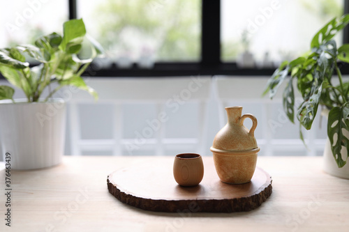 Wooden cup with clay tea pot on wooden table and green plants inddor 