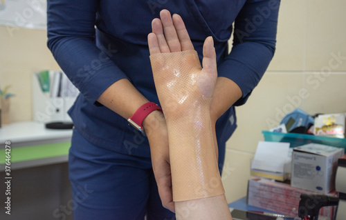 White orthosis for the hand. Hand therapy. A doctor in a blue work suit.