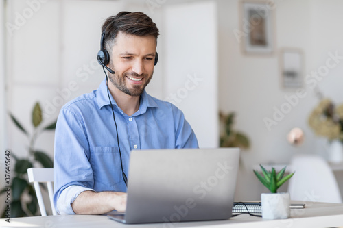 Call center operator at work. Male manager wearing headset and using laptop photo
