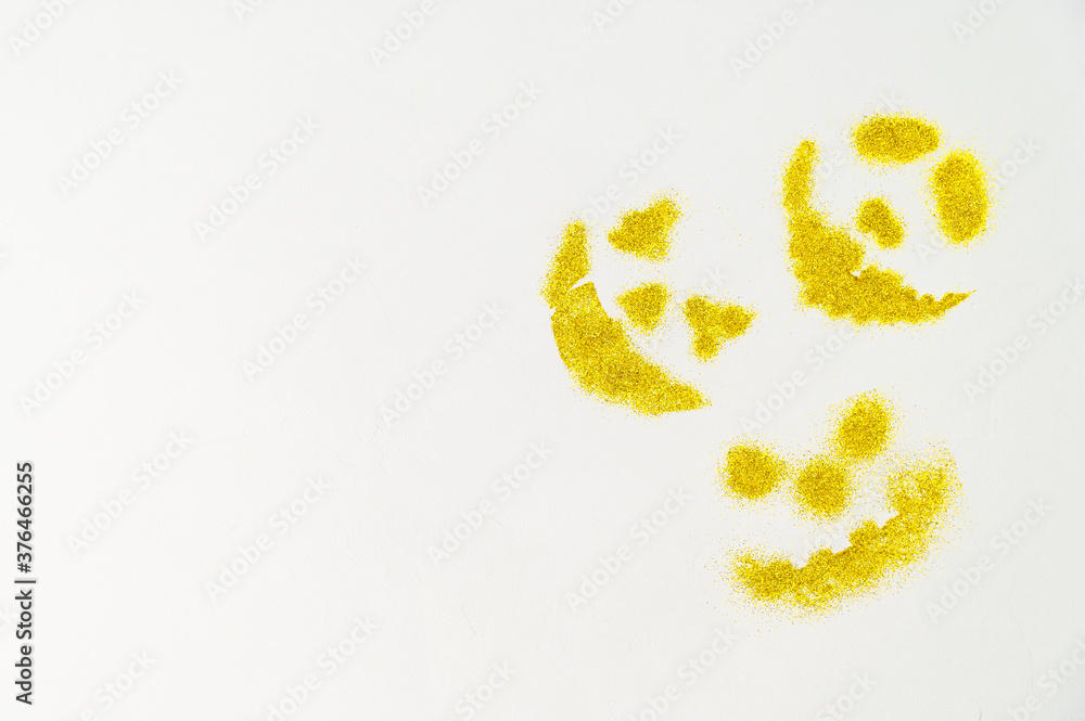 Halloween background. Three scary faces of pumpkins made of golden glitters on a white background. Top view, Copy space. Halloween background. Three scary faces of pumpkins made of golden glitters on a white background. Top view, Copy space.