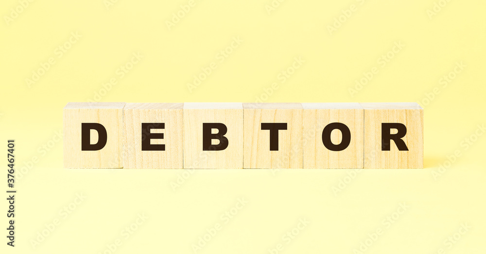 word debtor with black letters on wooden cubes on yellow word debtor with black letters on wooden cubes on yellow