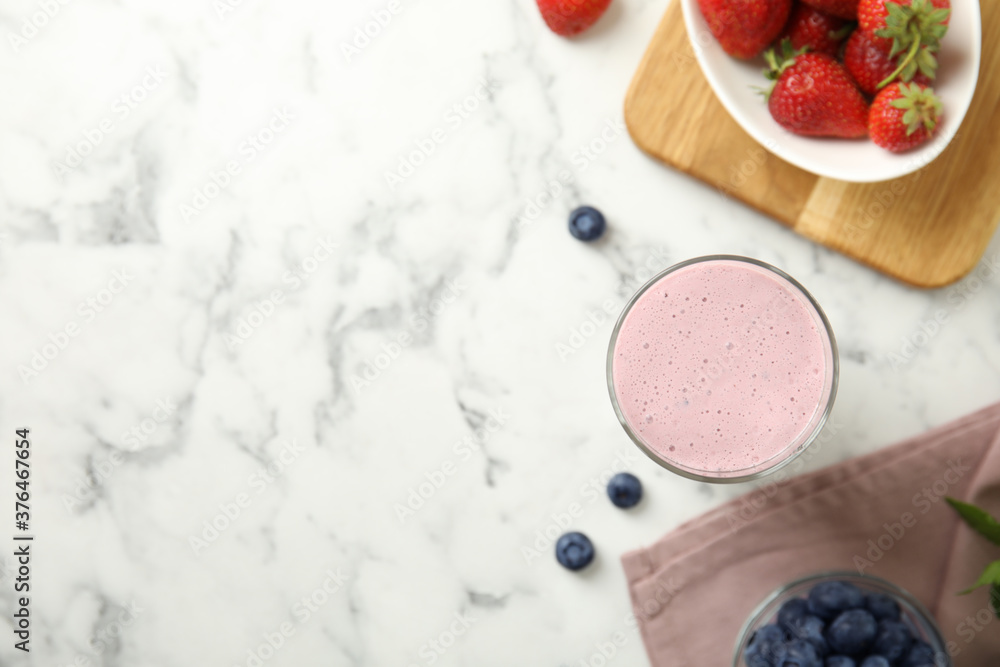 Tasty milk shake and berries on white marble table, flat lay. Space for text Tasty milk shake and berries on white marble table, flat lay. Space for text