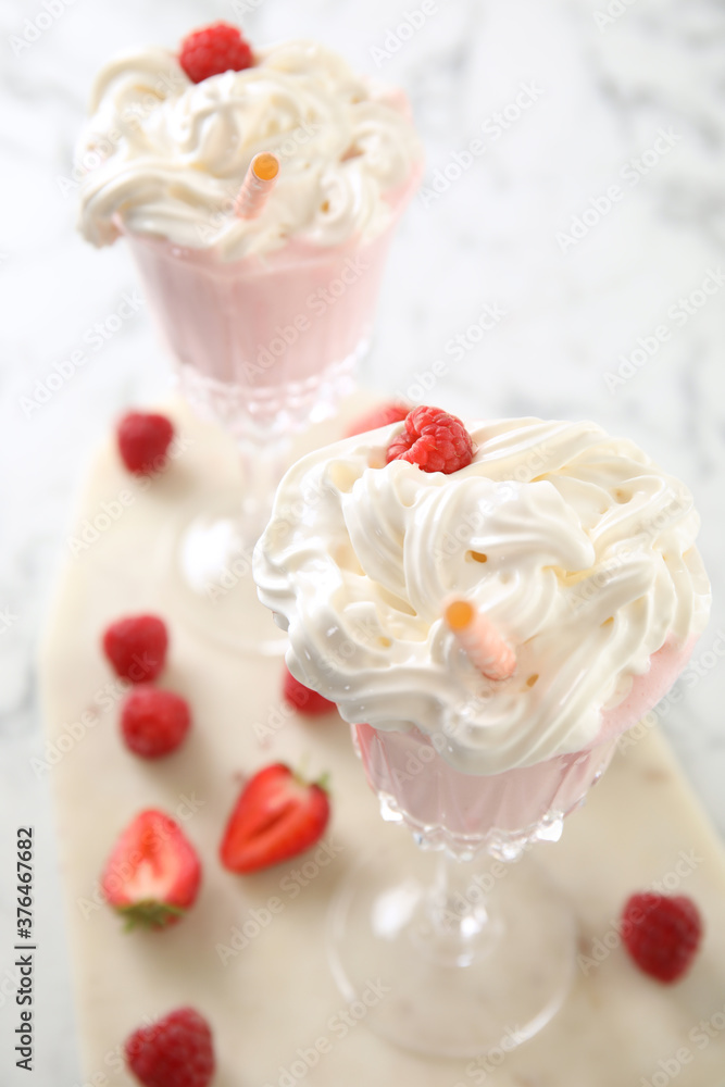 Tasty milk shake with whipped cream and fresh berries on light table, closeup Tasty milk shake with whipped cream and fresh berries on light table, closeup
