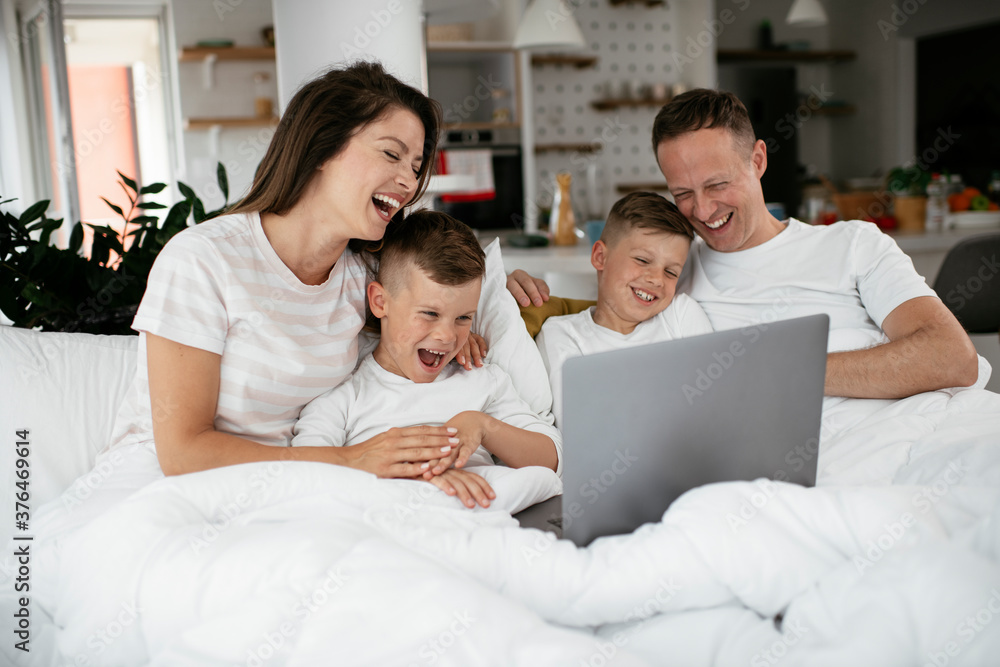 Beautiful parents with kids enjoying at home. Young family watching movie on lap top.. Beautiful parents with kids enjoying at home. Young family watching movie on lap top..