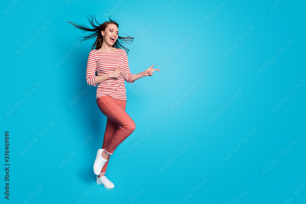 Incredible discounts ads. Full size photo of cheerful girl promoter indicate promo point index finger copyspace wear white trousers footwear isolated over blue color background Incredible discounts ads. Full size photo of cheerful girl promoter indicate promo point index finger copyspace wear white trousers footwear isolated over blue color background