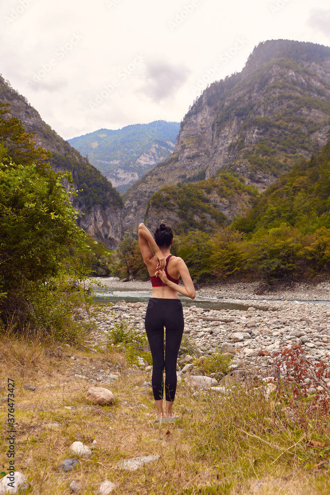 Yoga classes in nature. A woman does yoga in the mountains, near a mountain river flows. The concept of playing sports alone. Social exclusion