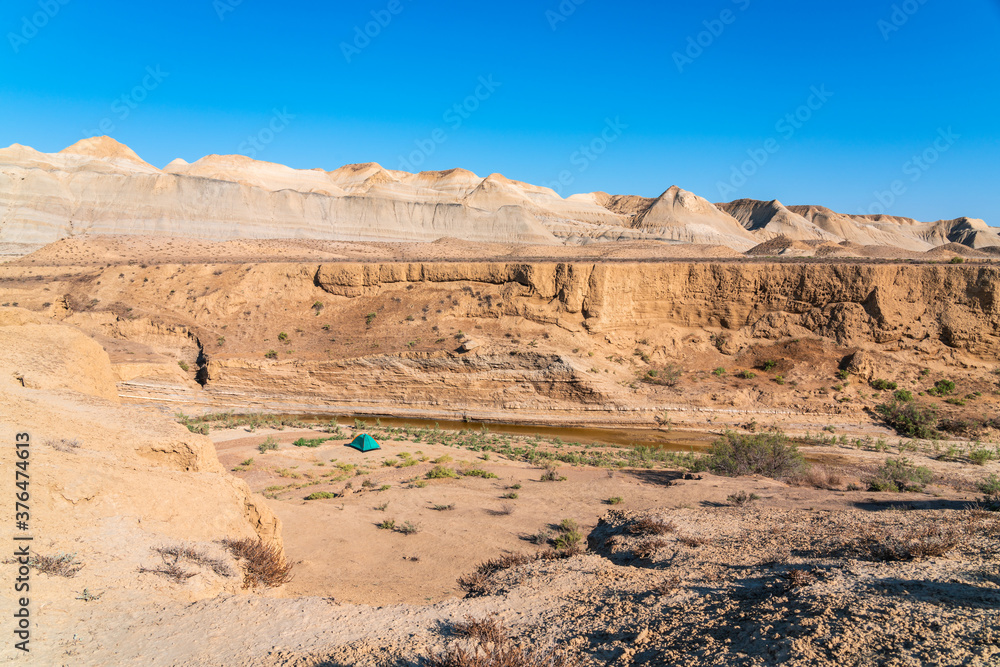 Tourist tent in a mountainous desert area by a small river Tourist tent in a mountainous desert area by a small river