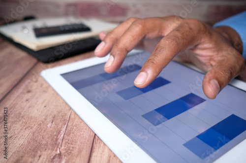close up of businessman's hand analyzing bar chart on digital tablet 