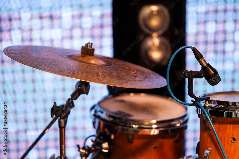Obraz premium MUSIC INSTRUMENTS DRUMS AND MICROPHONE ON STAGE, IN BACKGROUND LIGHT BARS. MUSICAL PERFORMANCE.