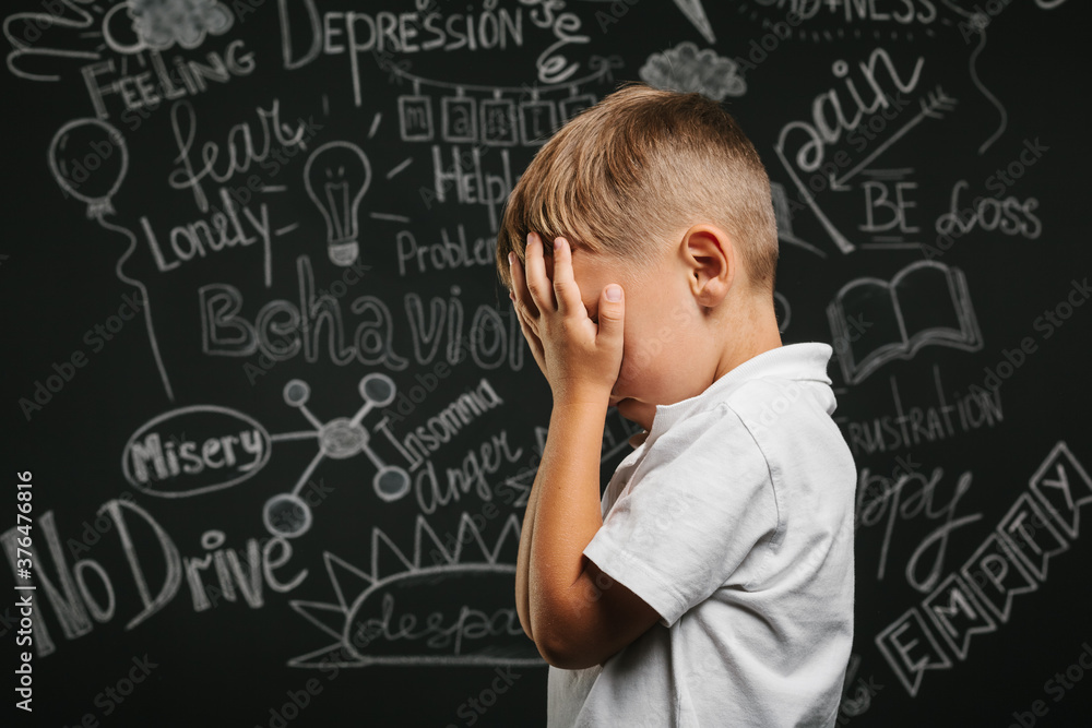 child whose depression is on a black background with his hands closed child whose depression is on a black background with his hands closed