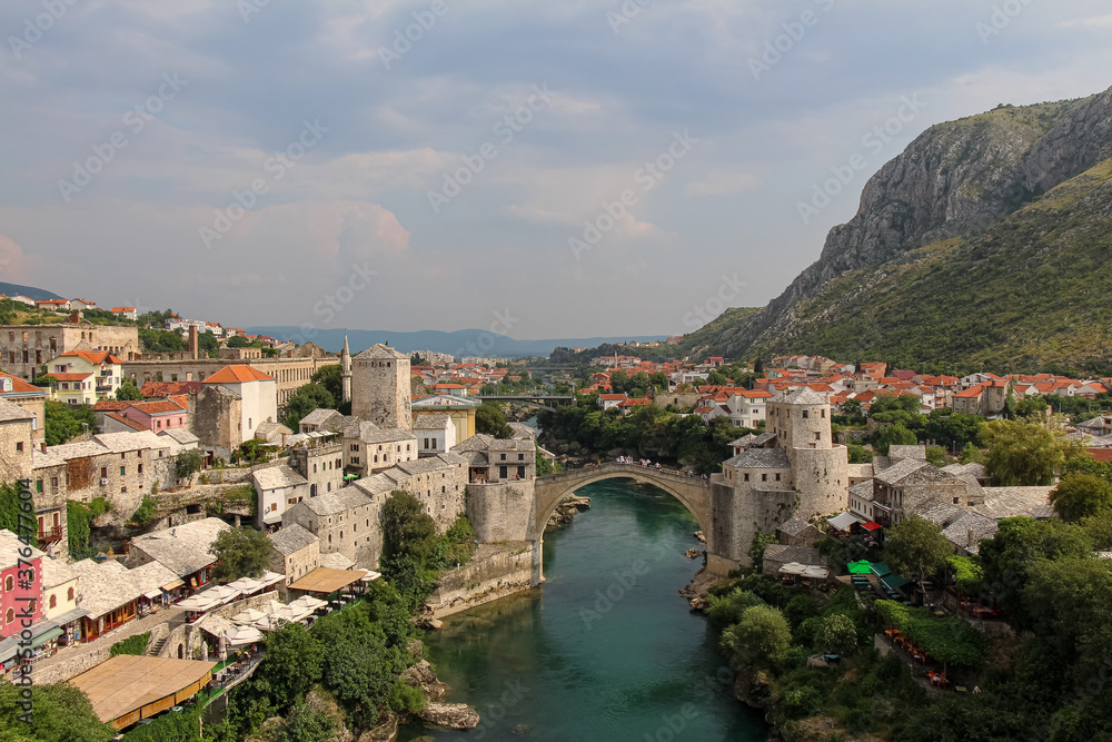 A landscape view of the old town of Mostar, with the old bridge over the river