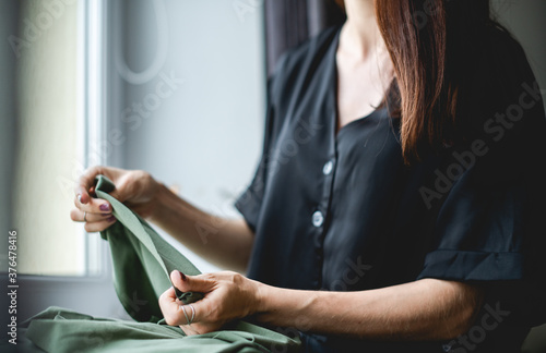 Selective focus of craftswoman holding green cloth near window 