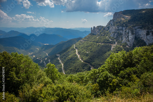 View from Col de Rousset in France. Winding road with twisties and sharp turns viewed from observation point on a cloudy day with some trees in the background. © Anze