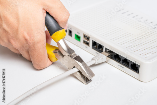 Hand with cutter cuts network cable to router. Internet connection disconnected. Concept of restricting access to information