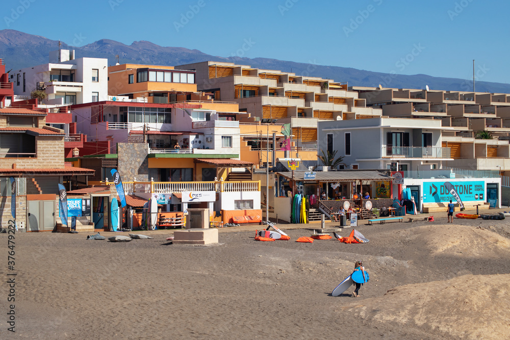 Picturesque residences and holiday homes in front of the surfing beach near Montana Roja, with few tourists enjoying at El Medano, Granadilla de Abona, Tenerife, Canary Islands, Spain