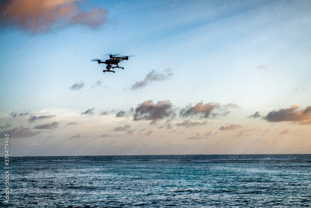 Drone silhouette flying over a tropical island. Vacation, travel and discovery concept