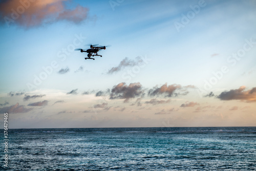 Drone silhouette flying over a tropical island. Vacation, travel and discovery concept