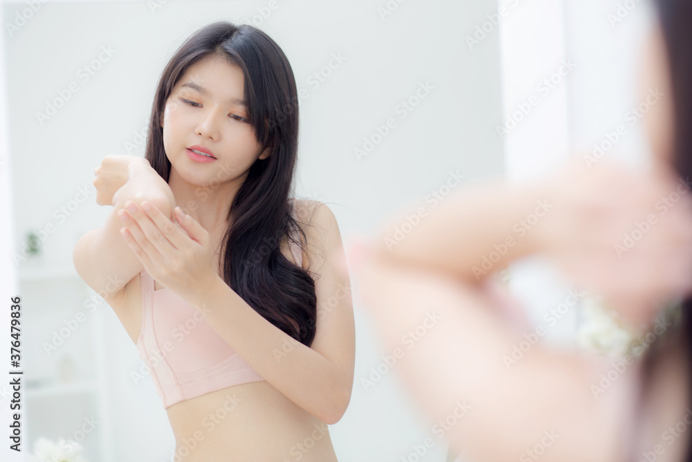 Beautiful sexy young asian woman looking mirror applying cream on elbow and message, beauty girl applying body lotion skin care for health and soft hydration, treatment and cosmetic with moisturizer. Beautiful sexy young asian woman looking mirror applying cream on elbow and message, beauty girl applying body lotion skin care for health and soft hydration, treatment and cosmetic with moisturizer.