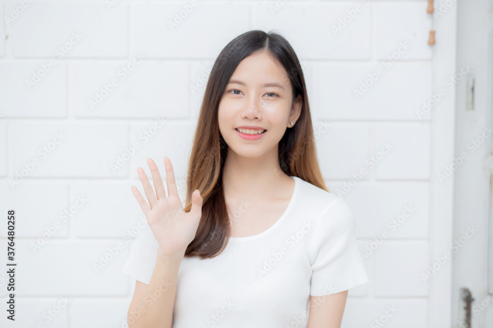 Beautiful young asian woman confident gesture say hello or greeting with waving her hand on cement background at home, friendly welcome, portrait girl cheerful expression happy and satisfied. Beautiful young asian woman confident gesture say hello or greeting with waving her hand on cement background at home, friendly welcome, portrait girl cheerful expression happy and satisfied.