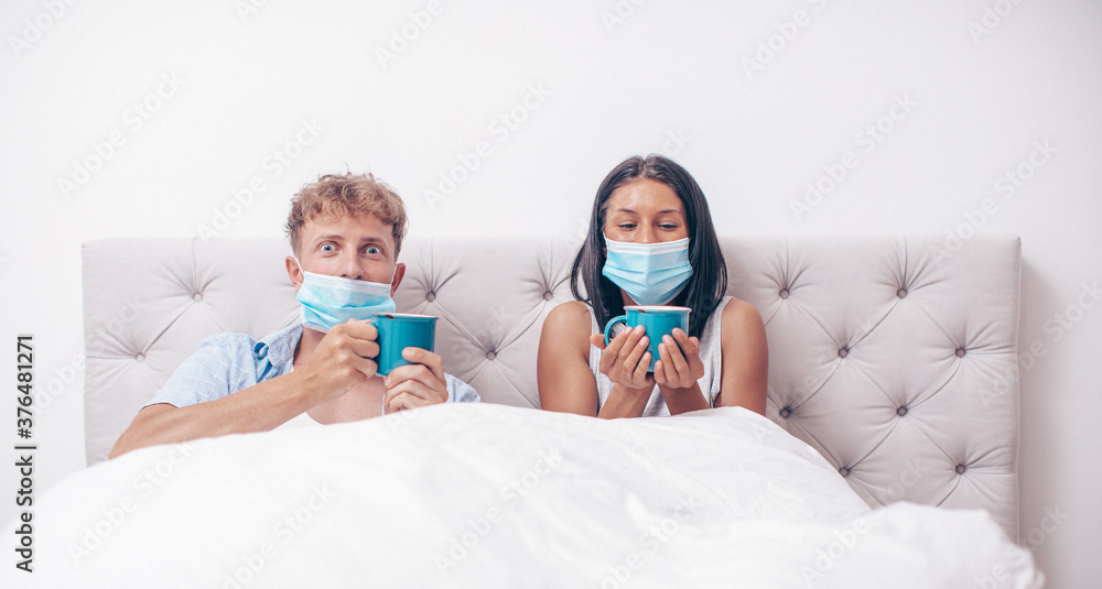 Young couple wearing a protective face mask. Couple in love. Mask. Coffee cups. Home concept. 