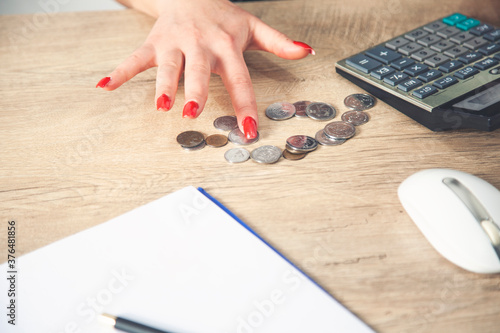Young girl sorting,grouping her coins on table with laptop beside.Young girl counting her money on her table with laptop.Young girl saving a money.Girl's creativity,imagination.