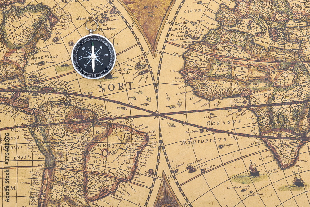 Classic round compass on background of old vintage map of world as symbol of tourism with compass, travel with compass and outdoor activities with compass