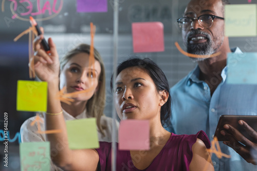 Young businesswoman writing on glass board at modern office photo